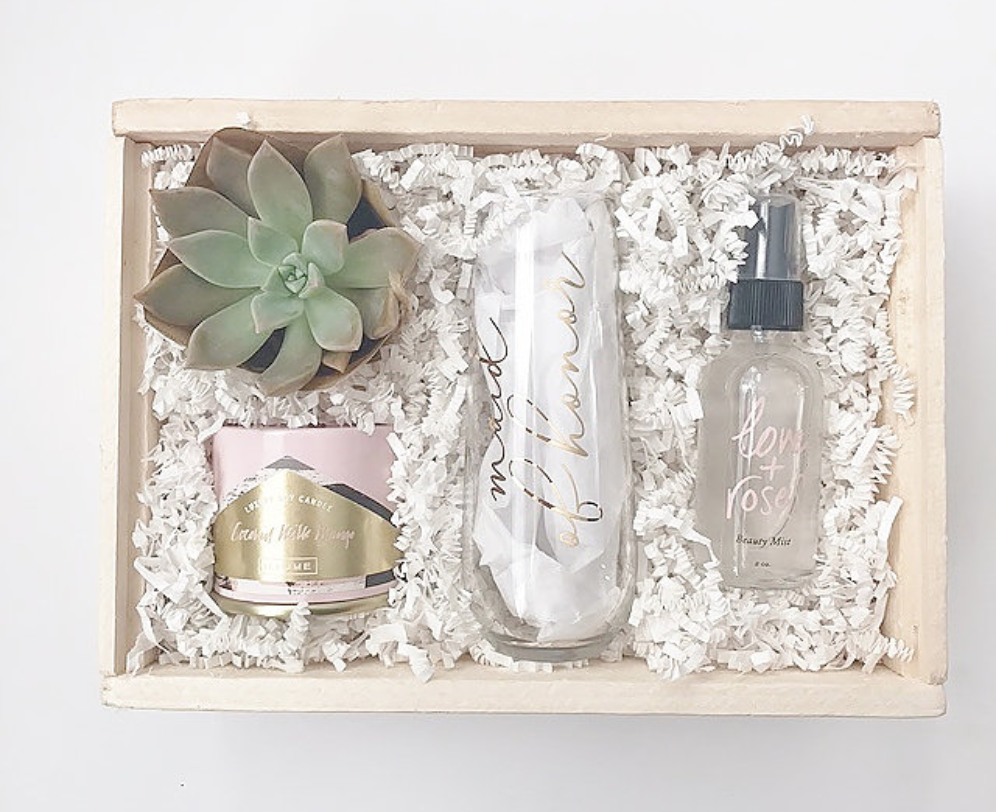 Bridesmaid gift ideas: wooden box with plant, candle, perfume, and champagne glass 