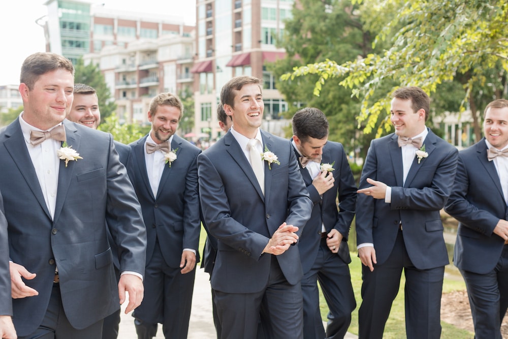 groom and groomsmen stand on a sidewalk